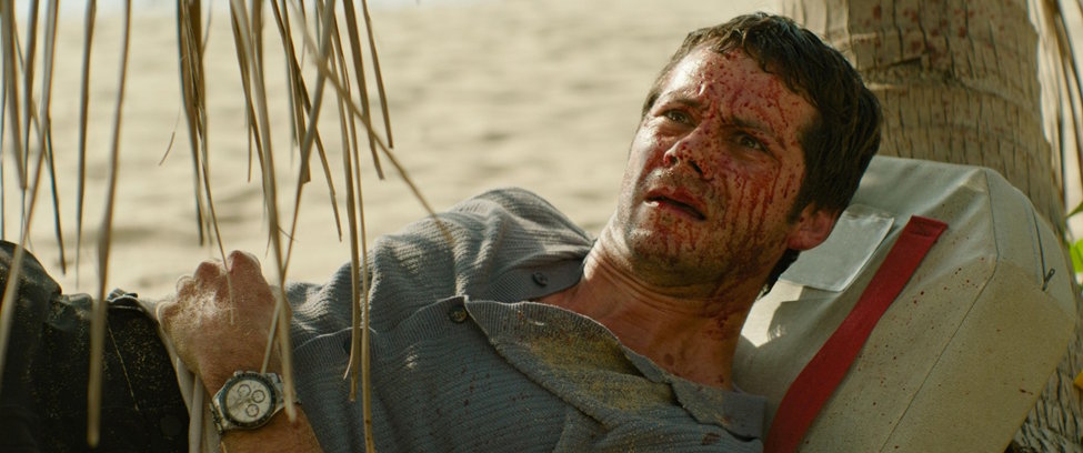A shot from Sam Raimi's "Send Help," depicting actor Dylan O'Brien washed up on a beach, covered in blood. The film is being reviewed by Ezekiel Yu for the automachination literary magazine.
